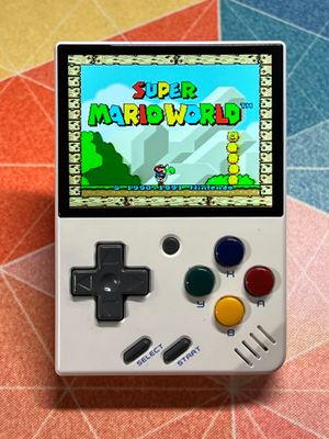 A Miyoo Mini v2 in white. It looks like a miniature Game Boy. The Super Mario World title screen is playing.